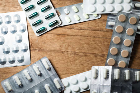Medical background backdrop with frame border of pills tablets drugs on wooden table. Pharmacy.の写真素材