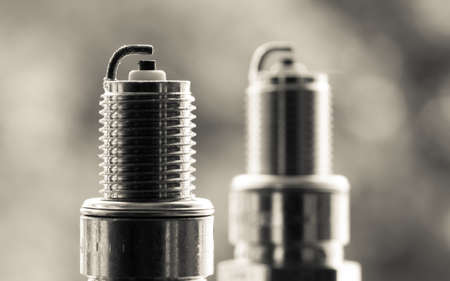 Auto service. Two new car spark plugs as spare part of auto transportation on blurry gray background.の写真素材