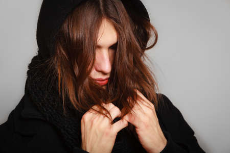 Men winter fashion. Handsome man long hair wearing black coat. Casual look. Studio shot on greyの写真素材