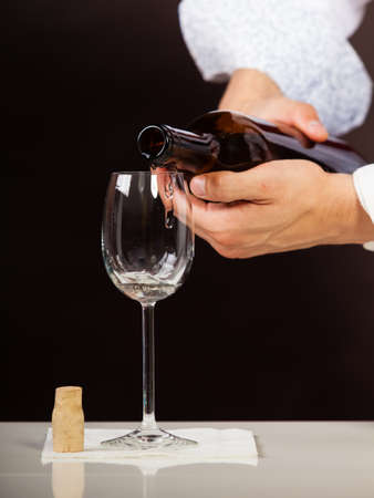 Male waiter or butler serving pouring white wine into glass.の写真素材