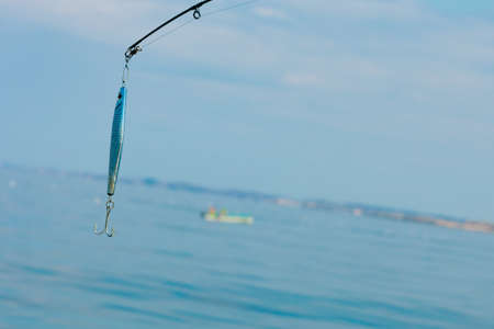Sport and recreation. Fishing bait - rod with wobbler against the blue sea water surfaceの写真素材
