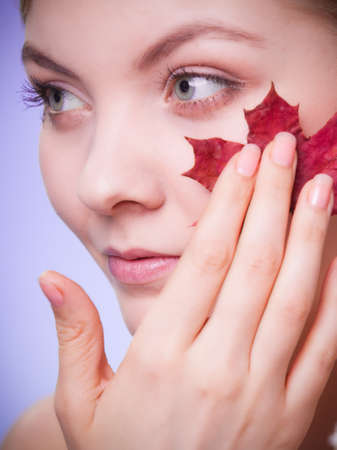 Skincare habits. Portrait of young woman with leaf as symbol of red capillary skin on violet. Face of girl taking care of her dry complexion. Studio shot.の写真素材