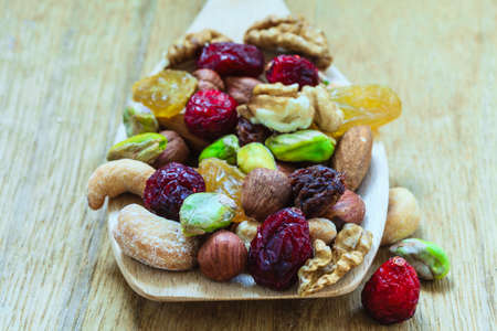 Healthy food organic nutrition. Closeup different varieties mix of dried fruits and nuts on wooden spoon.の写真素材