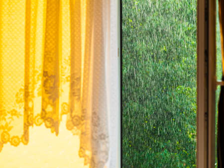 Summer rainy outside window, water drops droplets raindrops on glass windowpane. Downpour rain.の写真素材