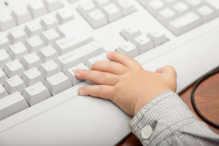 Happy childhood. Closeup of hand of smart little boy child kid on the computer keyboard at home. Technology.の写真素材