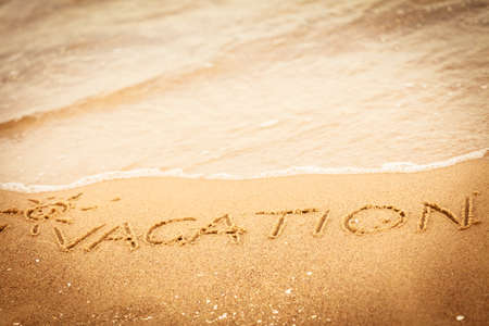 Holidays summer concept. The word vacation written in the sand on beach.の写真素材