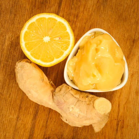 Time for make ginger tea. Fresh raw ginger rhizome root, honey and lemon on wooden rustic table.の写真素材