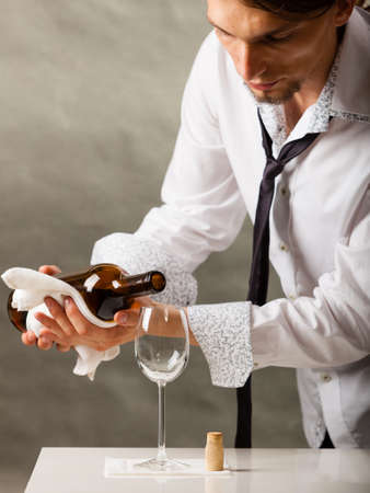 Male waiter or butler serving pouring wine into glass.の写真素材