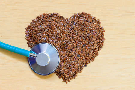 Diet healthcare and checkup concept. Raw flax seeds linseed heart shaped and stethoscope. Healthy food for preventing heart diseases.の写真素材