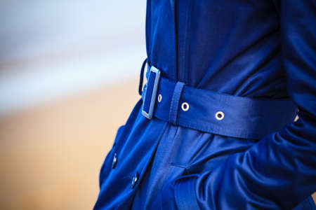 Female fashion. Closeup Fashionable girl in dark navy blue coat with belt. Clothing detail. Part of body.の写真素材