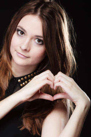 Love valentine's day concept. Woman teen girl doing forming heart shape love symbol with her hands on blackの写真素材