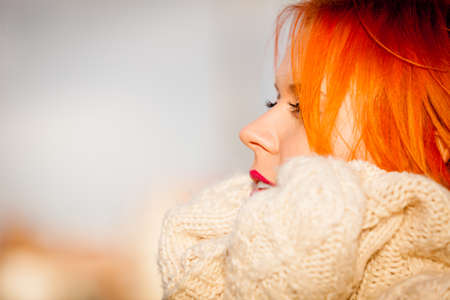 Winter fashion. Beauty face portrait redhaired young woman in warm clothing outdoor enjoying sunlight on sunny day.の写真素材