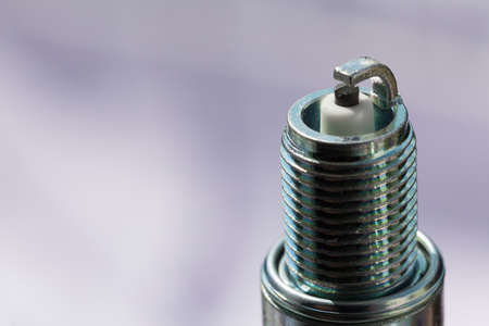 Auto service. New car spark plug as spare part of auto transportation on gray background.