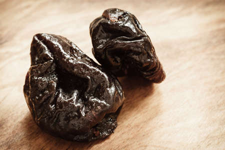 Healthy food, good cuisine. Closeup dried plums prunes fruits on wooden spoon rustic table backgroundの写真素材