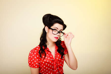Retro. Portrait of stylish young woman student or teacher in eyeglasses on yellow. Brunette girl in pinup style. Education.の写真素材