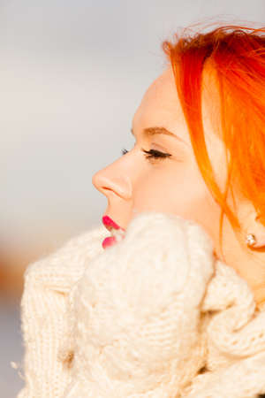 Winter fashion. Beauty face portrait redhaired young woman in warm clothing outdoor enjoying...