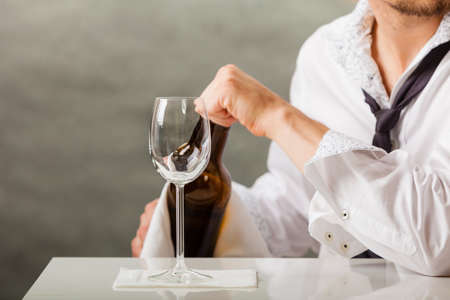 Male waiter or butler serving pouring wine into glass.の写真素材