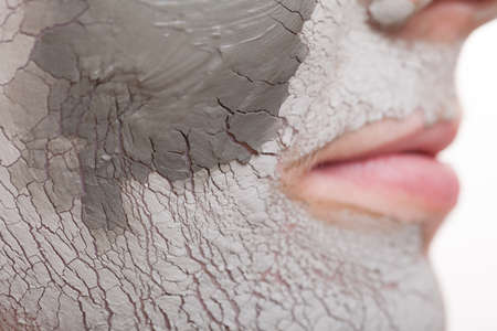 Skin care. Closeup of female face. Young woman applying clay mask. Girl taking care of her dry compexion. Isolated. Spa and beauty treatment.の写真素材