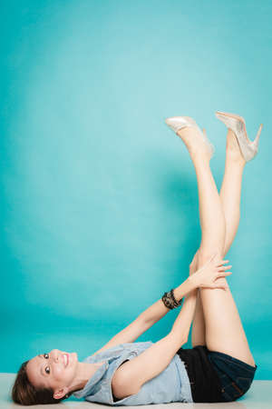 Vacation and summer fashion. Full length fashionable sexy girl in high heels relaxed with her legs raised up, on blueの写真素材