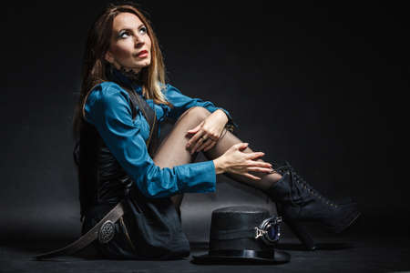 Full length steampunk retro woman with cylinder studio shot grunge dark backgroundの写真素材