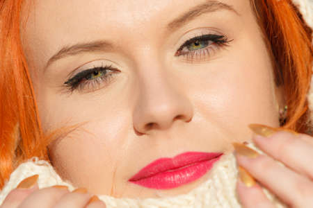 Winter fashion. Close up beauty face portrait red hair young woman in warm clothing white hood on head outdoor enjoying sunlight on sunny day.の写真素材