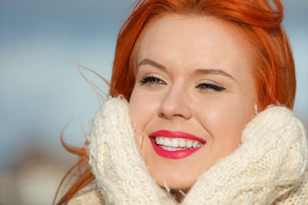 Winter fashion. Beauty face portrait red hair young woman in warm clothing outdoor enjoying sunlight on sunny day.の写真素材