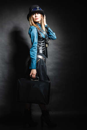 Full length steampunk retro woman with bag suitcase studio shot grunge dark backgroundの写真素材