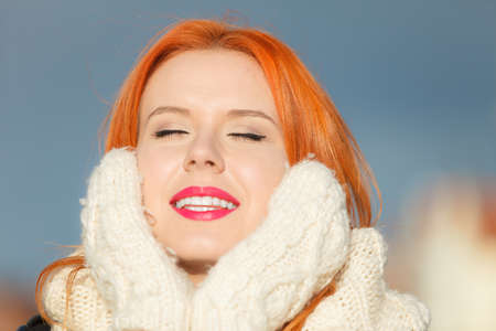 Winter fashion. Beauty face portrait red hair young woman in warm clothing outdoor enjoying sunlight on sunny day.の写真素材