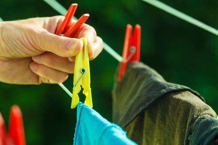 Housework. Woman hand hanging clean wet laundry to dry on the rope clothes line outdoor.の写真素材