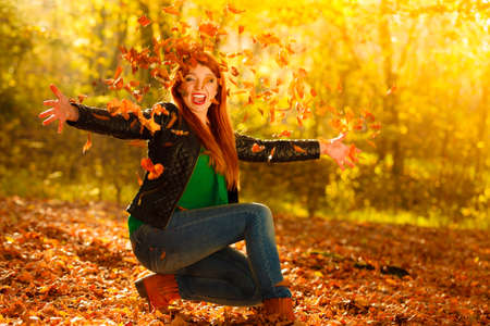 Happiness carefree leisure concept. Redhaired long hair woman relaxing in autumn park throwing...