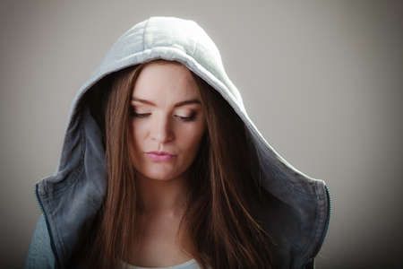 Portrait of young woman teen girl long hair  in hooded sweatshirt on gray background