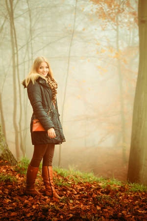 Woman with handbag walking relaxing in foggy day in romantic autumn forest park outdoorの写真素材