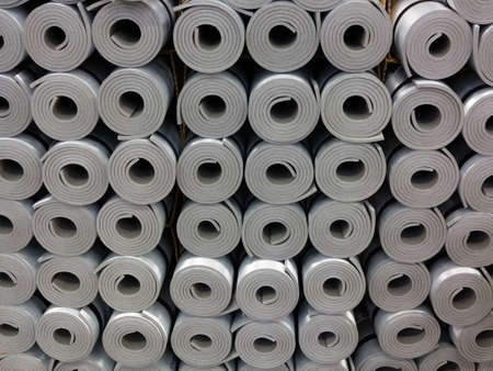 Closeup of a lot of rolled up gray foam sleep mats camping beds or fitness yoga equipment as background. Travel and sport.の写真素材
