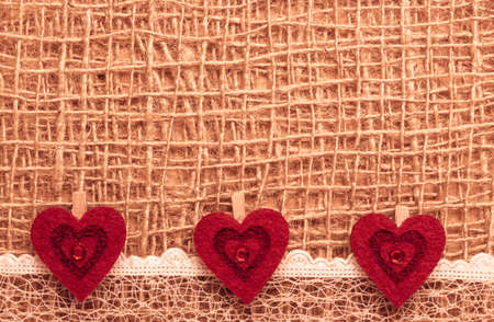 Valentines day or wedding concept. Red decorative hearts lace ribbon on rustic linen cloth background with copy space. Vintage aged styleの写真素材