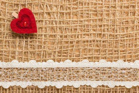 Valentines day or wedding concept. Red decorative heart lace ribbon on rustic linen cloth background with copy space. Vintage aged styleの写真素材