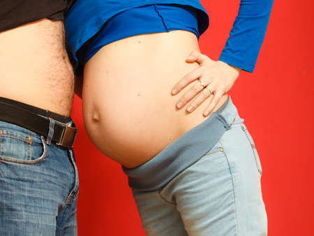 Pregnant woman and her husband. Mom and dad touch each other with their bellies, side viewの写真素材