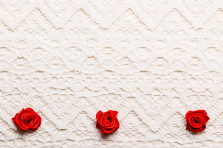 Valentines day wedding, invitation or greeting card. Red decorative satin rose flowers on white cloth lace backgroundの写真素材