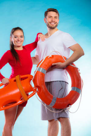 Accident prevention and water rescue. Young man and woman lifeguard couple on duty holding buoy lifesaver equipment on blueの写真素材