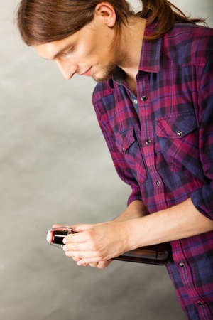young man holding a beer bottle on grey backgroundの写真素材