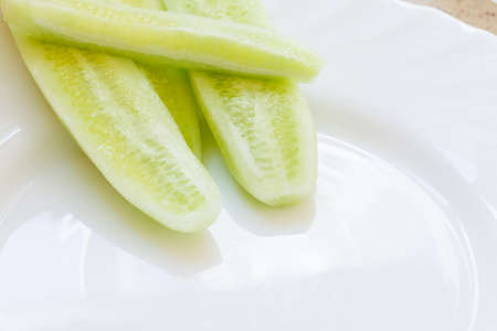 Vegetarian food. Fresh cucumber pieces on white plate. Dinner preparing.の写真素材