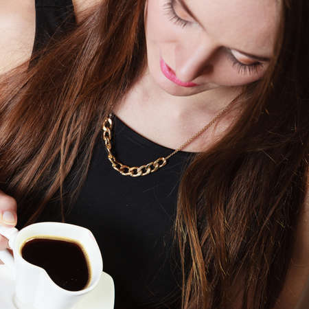 Beautiful young girl holding heart shaped cup of coffee drinking, unusual high angle viewの写真素材