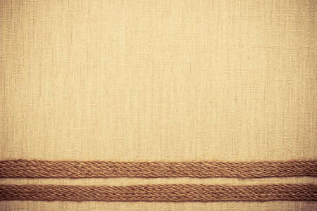 Jute bagging ribbon on bright fabric textile material, natural linen backgroundの写真素材