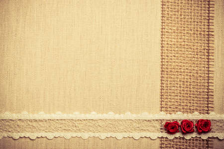 Valentines day, wedding, invitation or greeting card. Red decorative silk rose flowers, lace ribbon on linen cloth. Border frame. Retro styleの写真素材