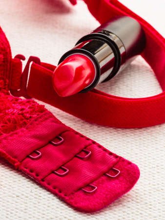 Woman beauty concept. Makeup supplies lipstick on red lace  brassiere lingerie. Lips cosmetic elegance.の写真素材