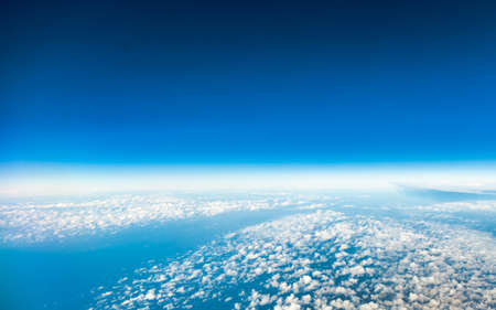 Blue sky. View from window of airplane flying in clouds. Skyscape cloudscape. Bird's eye.