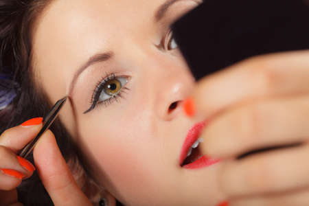 Closeup part of face, woman plucking eyebrows depilating with tweezers. Girl tweezing eyebrows.の写真素材