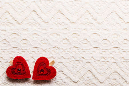 red decorative hearts love symbol on white cloth lace backgroundの写真素材