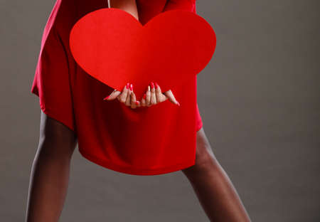 Valentines day love health or charity concept. Woman holding big heart love symbol dark gray backgroundの写真素材