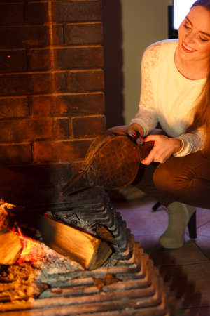 Winter at home, heating. Young woman beauty long hair girl relaxing warming up at fire fireplace, doing flame. Indoor.の写真素材