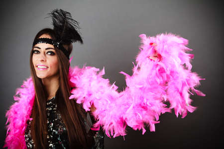 Retro flapper woman on carnival time. Young female with pink plume and black feather on head. Studio...
